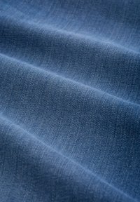 Tessuto denim di colore blu profondo, che mostra una texture liscia con leggere variazioni e fini motivi di tessitura.