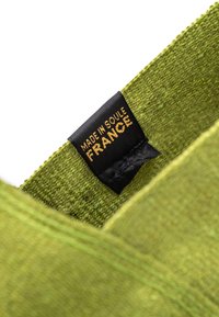 Tissu tricoté vert avec une finition texturée, présentant une étiquette noire portant la mention "FABRIQUÉ À SOULÉ EN FRANCE" en lettres dorées.