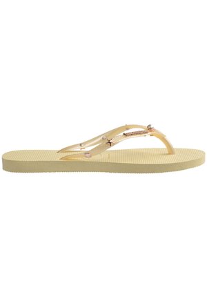 Tongs jaunes avec une semelle texturée, des sangles transparentes ornées d'accents en perles et en étoiles, et un design lisse et minimaliste.