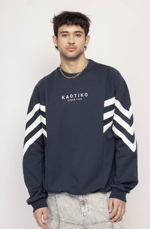 Tume kampsun valgete diagonaalsete triipudega varrukatel. Ümmargune kaelus ja pehme tekstuur. Omab trükitud logo, mugavat lõiget ja soonikuid varrukatel.