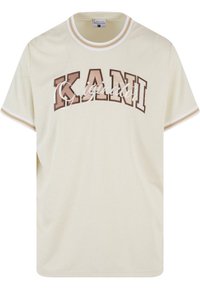Cremfarvet t-shirt med en struktureret finish, prydet med brune blokbogstaver "KANI" og "Original" i kursiv. Kantet med hvide striber.