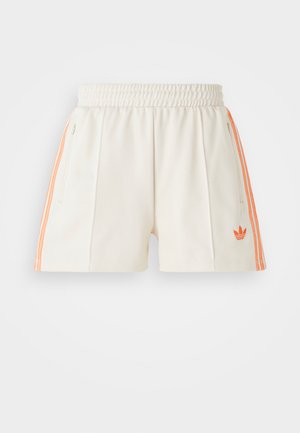 Bele atletske kratke hlače z elastičnim pasom, ki imajo oranžne stranske črte in vezeno logotip na levem robu. Gladka tekstura tkanine.