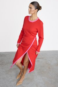Rotes Strickkleid mit langen Ärmeln, rosa Rüschendetails am Ausschnitt und an der Seite, asymmetrischer Saum und einem Schlitz bis zur Oberschenkelhöhe.