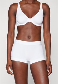 White bra and matching shorts made from smooth fabric. Bra features a molded shape, adjustable straps, and wide waistband on shorts.