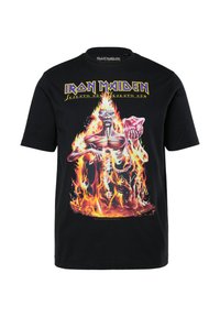 Černé bavlněné tričko s grafickým potiskem postavy obklopené plameny, s nápisem "IRON MAIDEN" v tučném žlutém písmu nahoře.