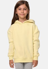 Felpa gialla con cappuccio e maniche lunghe, realizzata in tessuto morbido. Presenta una vestibilità comoda e polsini a coste. I leggings grigi completano l'outfit.