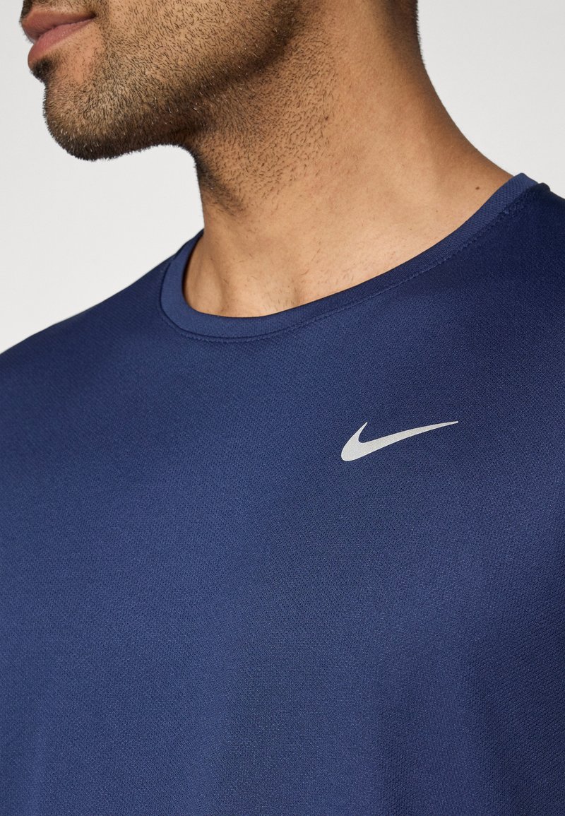 Marineblaue Sportshirt mit rundem Ausschnitt und kurzen Ärmeln, gefertigt aus einem strukturierten Material. Verfügt über ein kleines silbernes Nike-Logo auf der Brust.