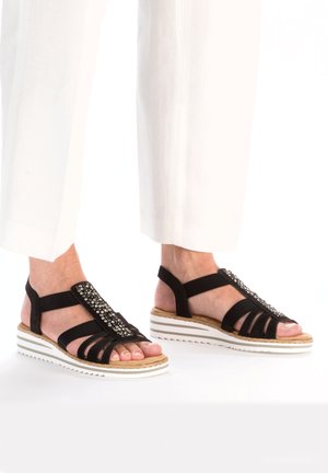 Black sandals with a textured strap and rhinestone accents, featuring a white and beige striped sole and an open design for breathability.