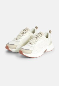 Białe siatkowe sneakersy z beżowymi akcentami i szarymi detalami. Gruba biała podeszwa oraz mała, brązowa pętla z tyłu. Logo Fila na języku.