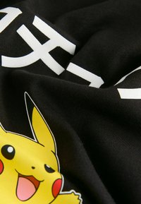 Must mustriba, millel on kollane multifilmilik Pikachu joonistus punaste põskedega ja suur valge tekst kaldega.
