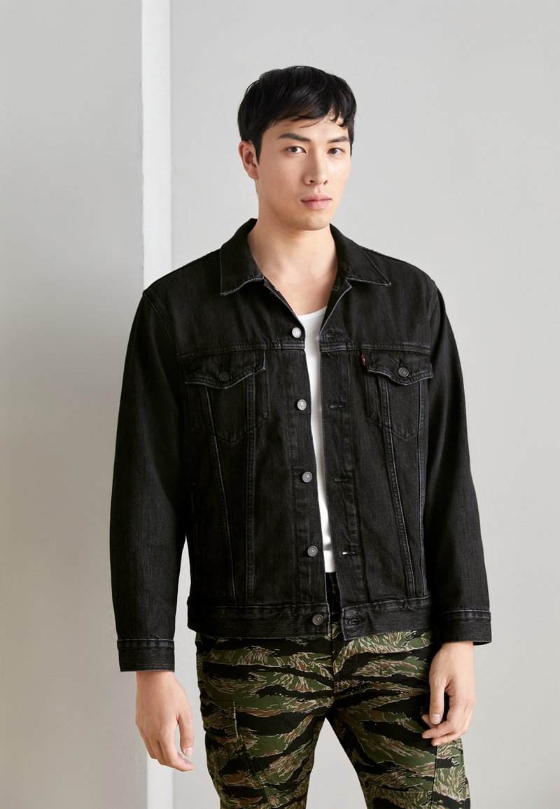 Jachetă din denim neagră, cu un design clasic cu nasturi fruntași, două buzunare pe piept și o croială dreaptă, asortată cu pantaloni cu un model camuflat.