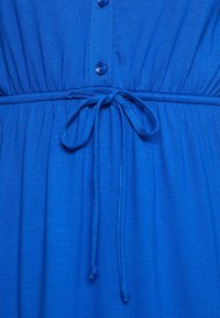 Niebieska sukienka z zapięciem na guziki z przodu, marszczonym stanem i paskiem z materiału. Miękka tekstura i gładkie wykończenie.