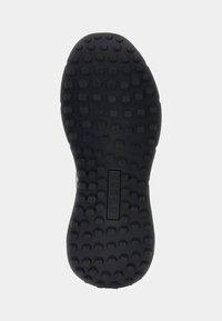 Semelle de chaussure noire avec des reliefs circulaires et une section rectangulaire au centre embossée avec le mot "GUESS."