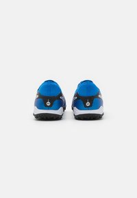 Zapatillas deportivas azules con un acento negro, tacón redondeado, suela texturizada y un mínimo detalle en blanco, diseñadas para el rendimiento y el soporte.