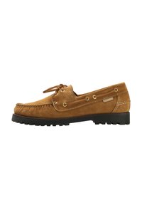 Chaussure en suede beige avec un design mocassin, présentant une semelle en caoutchouc noir plat, des lacets en cuir et des œillets en ton or.
