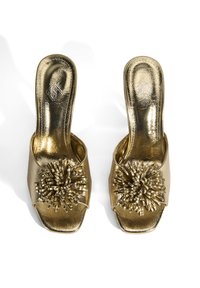 Gouden metallic open-teensandalen met een gestructureerde afwerking en een grote decoratieve bloemaccent van strapmateriaal. Vierkante vorm.