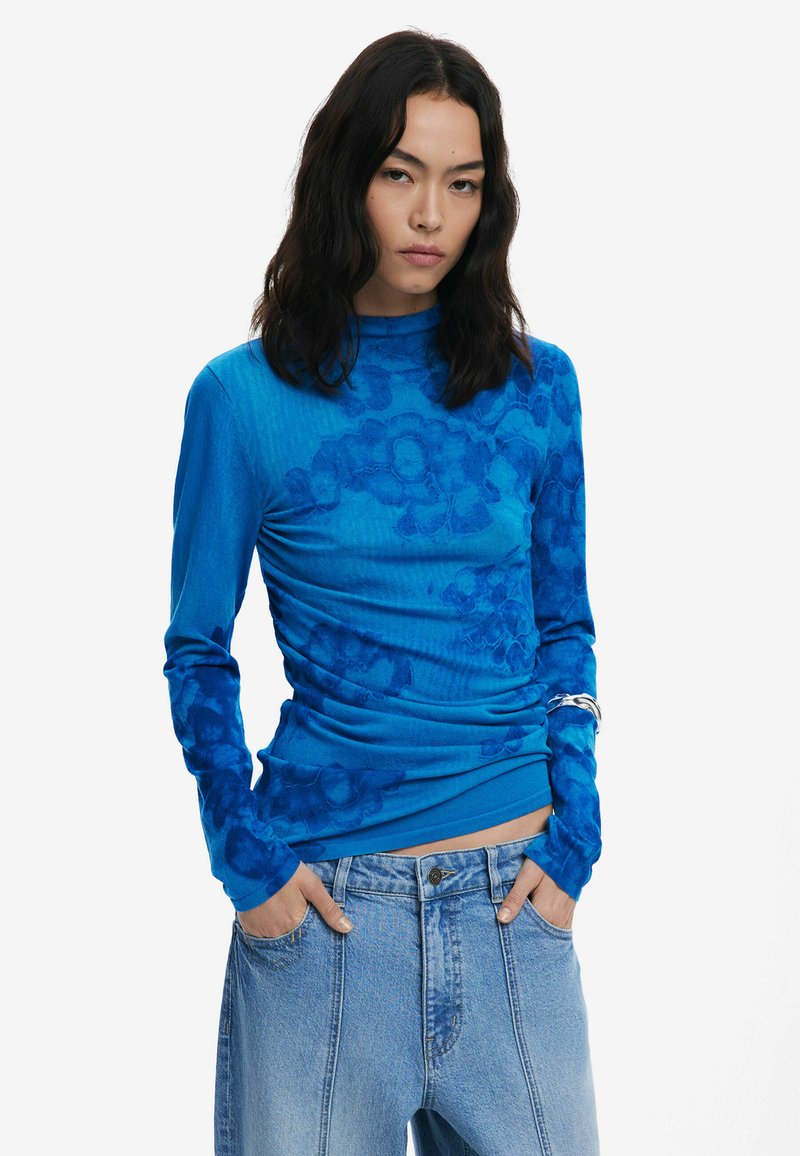 Blaues Langarmoberteil mit floralem Muster, aus einem weichen, strukturierten Stoff gefertigt. Verfügt über ein figurbetontes Design und einen hohen Kragen.