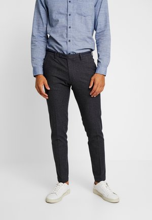 Donkergrijze geruite broek met een slim fit, voorzien van een tailleband en voorzakken, gecombineerd met een lichtblauw overhemd met knopen en witte sneakers.