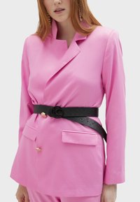 Fuchsia rosa kavaj med en figursydd design, två framfickor och detaljer i guldknappar. Matchad med ett svart texturerat bälte med en logobuckle.