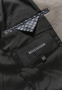 Vest din țesătură neagră cu un batic din satin de culoare albastră, având un model floral alb. Eticheta spune "Matinique" și este vizibilă eticheta de mărime.