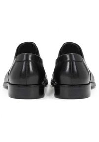 Paire de chaussures de cuir noir poli formelles vues de dos sur un fond blanc.