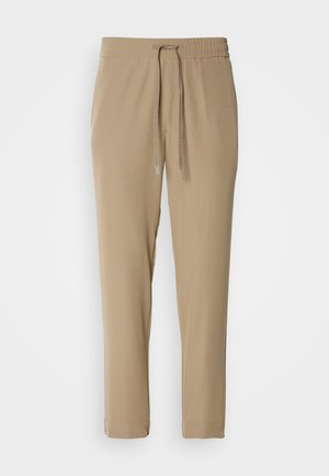 Beige joggebukser med elastisk liv og snor. De har en tapered design og ribbestrikkede hem, laget av lett stoff.