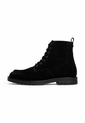 Black suede lace-up ankle boot with pull tab and low stacked heel, side view on white background.