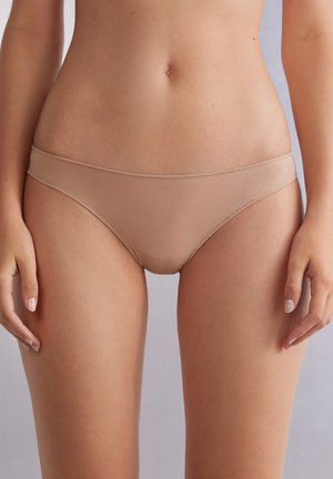 Beige Unterwäsche mit einem minimalistischen Design, das eine glatte Textur, einen niederen Schnitt und einen elastischen Bund aufweist und einen nahtlosen Look betont.