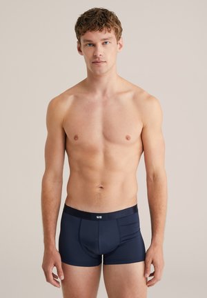 Boxer briefs de color azul marino, fabricados con un tejido suave; diseño ajustado con una cinturilla blanda que presenta un logo blanco en la parte frontal.