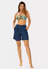 Kwiatowy bikini bandeau z lekkim wypełnieniem i cienkimi ramiączkami, w zestawie z ciemnoniebieskimi, sięgającymi kolan szortami z bocznymi kieszeniami i zapięciem na guzik.