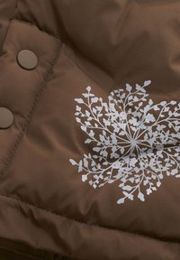 Brown padded fabric with a glossy white floral pattern. Features two round brown buttons at the seam. Soft texture with visible stitching.