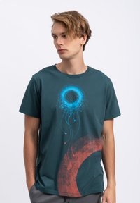 Teal katoenen T-shirt met een blauwe ronde afbeelding en een rood abstract ontwerp met druppels, standaard pasvorm, korte mouwen.