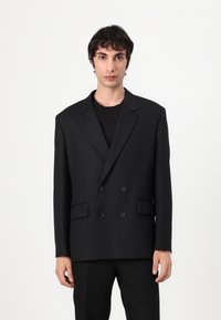 Black double-breasted blazer made of smooth fabric, featuring a notched lapel, two front pockets, and black buttons. Straight cut design.