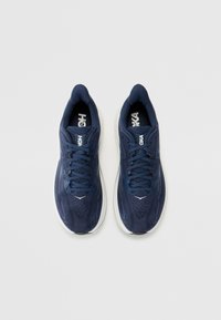 Scarpe da ginnastica blu navy con tomaia in rete, suola bianca e design con lacci. Presentano aree con texture e branding sulla linguetta.