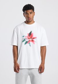 Camiseta de algodón blanca con un diseño floral difuminado en rosa y verde, con el texto "El Jardín Botánico, Central Park, NY" impreso.