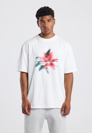 Witte katoenen t-shirt met een vervaagd bloemmotief in roze en groen, met de tekst "De Botanische Tuin, Central Park, NY" gedrukt.