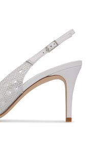 Sandal con tacco alto bianco con design a intagli e decorazioni di borchie. Include una cintura regolabile alla caviglia e una finitura liscia.