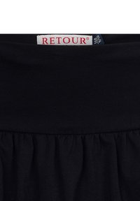 Schwarze Skirt mit einem gerafften unteren Saum, ausgestattet mit einem breiten elastischen Bund. Ein auffälliges weißes Etikett mit "RETOUR" ist sichtbar.