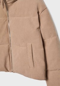 Beżowa, żeberkowa kurtka o skróconym fasonie, z zamkiem błyskawicznym, bocznymi kieszeniami i teksturowanym materiałem, prezentująca gładkie wykończenie i uporządkowaną sylwetkę.