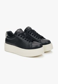 Zwarte leren platform sneakers hebben een glad bovenwerk, ronde neus, dikke witte zool en zwarte veters met oogjes. Gevoerde hakaccenten.