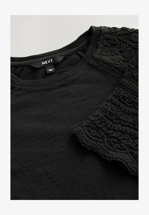 T-shirt noir avec un col rond et des manches brodées texturées noires, fabriqué à partir d'un tissu doux avec une finition lisse.
