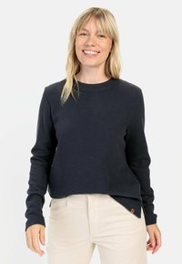 Mørkeblå vaffelmønstret sweater med rund hals og lange ærmer, der har en afslappet pasform og sidespalter ved nederste kant.