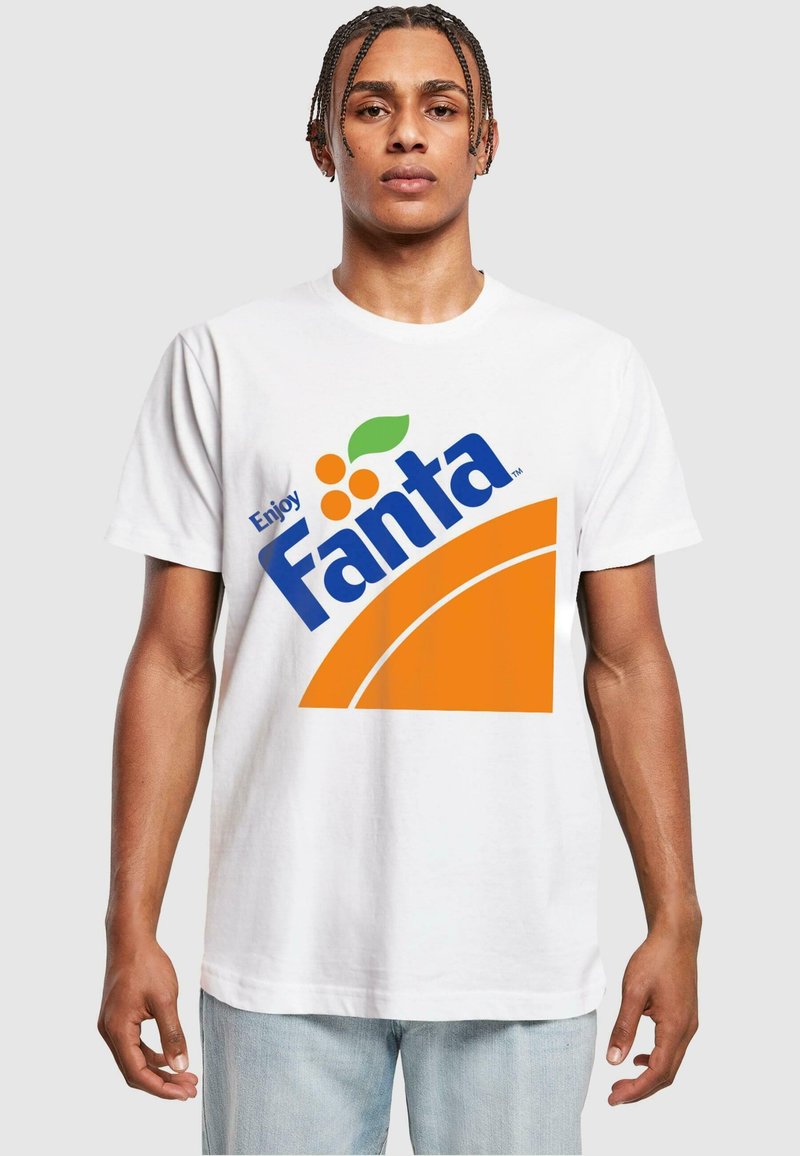Hvid t-shirt med et stort Fanta-logo i blå og orange, med orange cirkelaccenter, båret af en person med fletninger.