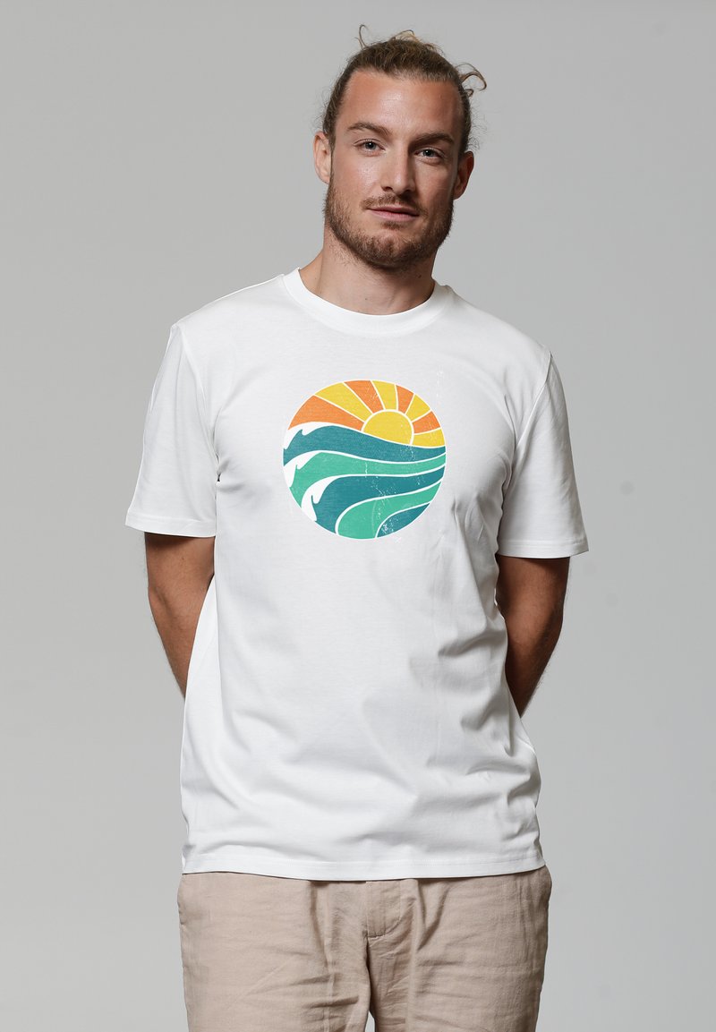 Witte katoenen t-shirt met een ronde grafische afbeelding van een zon in oranje en geel, en groene gestileerde golven. Korte mouwen, ronde hals.