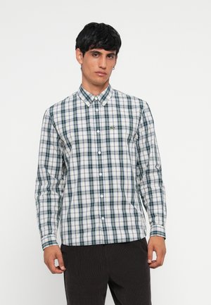 Camisa de cuadros blanca y verde de manga larga con cuello abotonado, que presenta un pequeño logo en el pecho y un dobladillo recto.