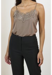 Ruskea satiiniyötoppi, jossa on pitsiyksityiskohtia kaula-aukossa, ohuet olkaimet. Yhdistetty räätälöityihin mustiin housuihin.