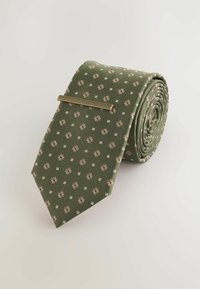 Cravate verte avec un petit motif floral et un design en grille. Tissu texturé, enroulée, avec un clip de cravate doré.