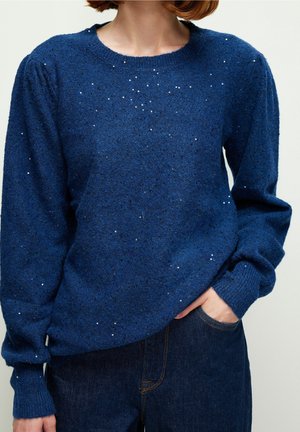 Pull en tricot bleu avec encolure ronde, manches longues, tissu texturé avec de petites paillettes, et bordures côtelées aux poignets et à l'ourlet.