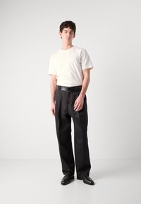 White short-sleeve t-shirt paired with black trousers and black shoes. The outfit is simple, featuring a classic fit and solid colors.