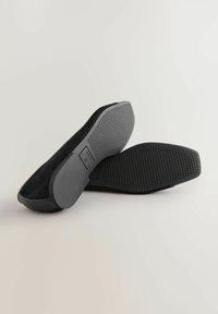 Scarpe in suede nero con suola in gomma nera testurizzata, caratterizzata da un motivo in rilievo per una migliore aderenza. Finitura liscia lungo i bordi e design minimalista.